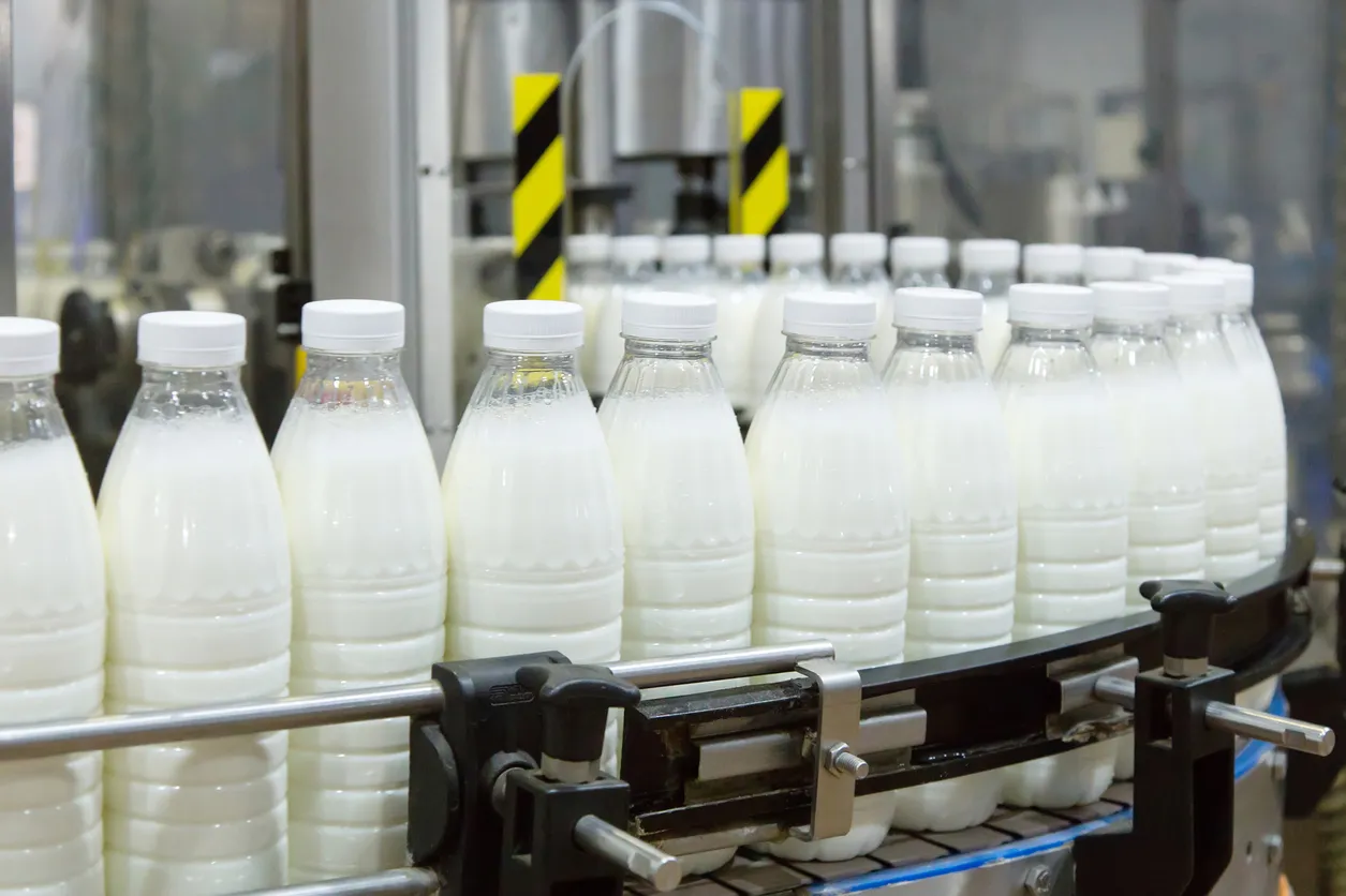 Fábrica que produce leche o yogur en botellas de plástico en la línea transportadora.