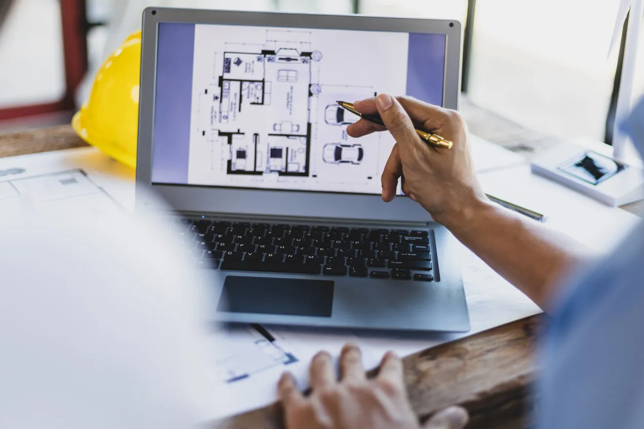El grupo de arquitectos e ingenieros de lluvia de ideas discute el diseño del plano del edificio en una computadora portátil 