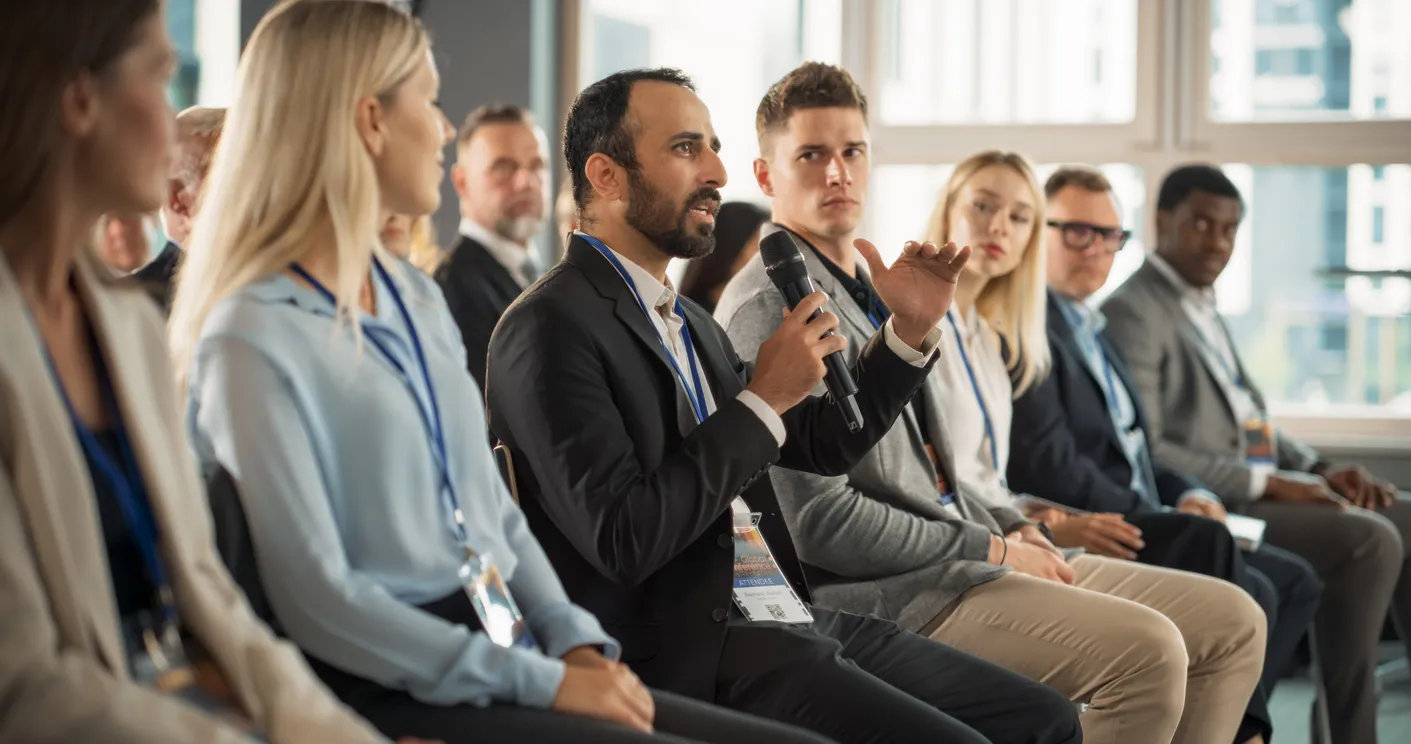 El asistente a la conferencia de tecnología masculina multiétnica se sienta en la multitud
