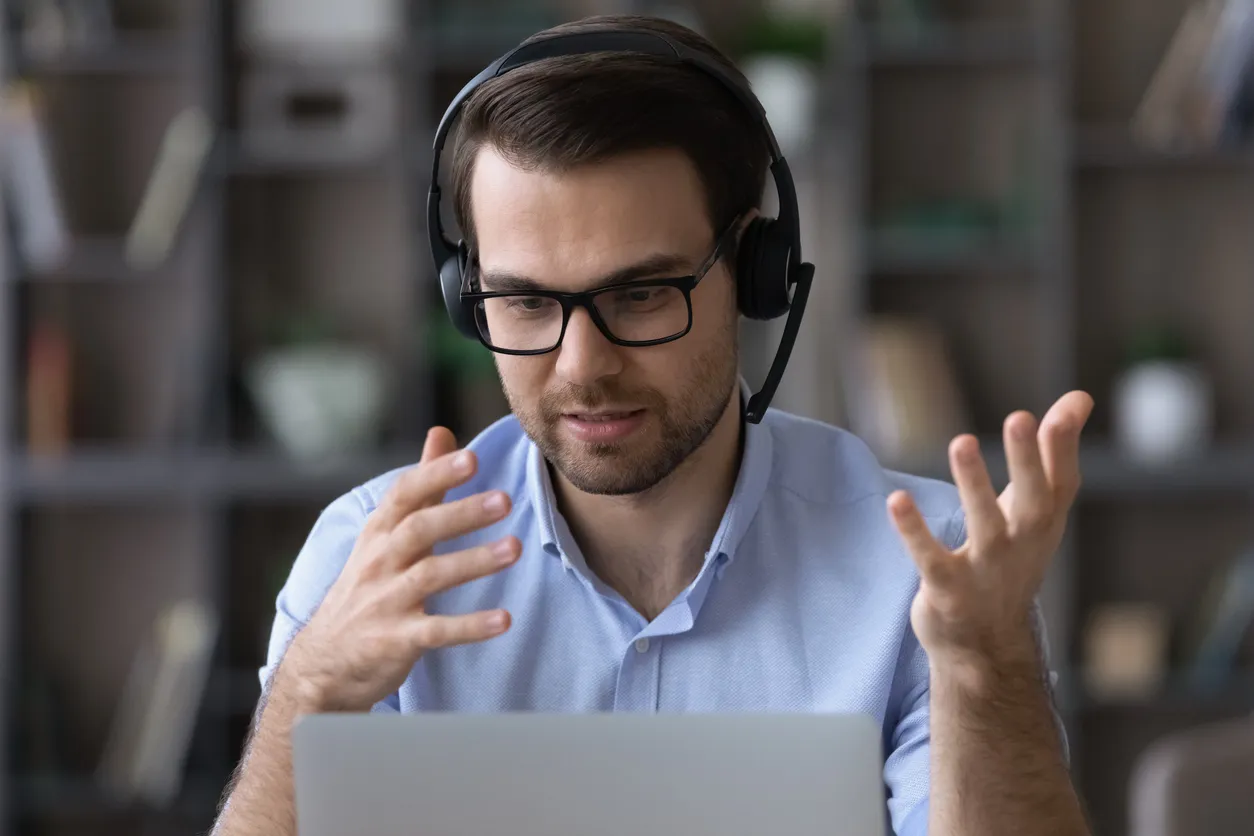 Hombre joven con auriculares habla por videollamada en la PC