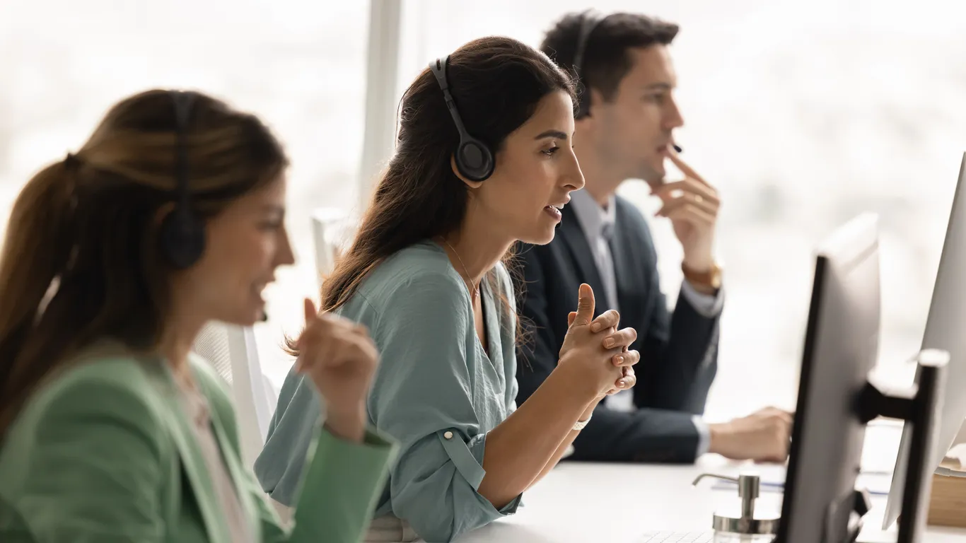 Mujer asistente telefónica sentada en el lugar de trabajo con colegas del centro de contacto 