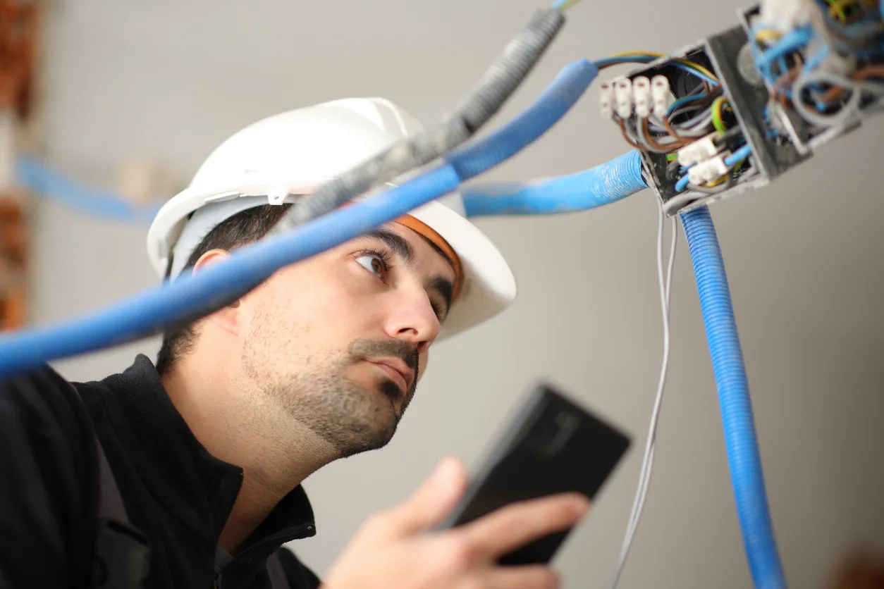 Electricista comprobando la instalación eléctrica con el teléfono