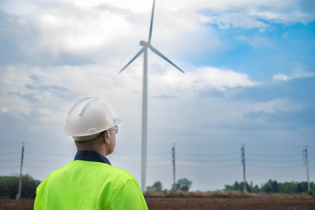 Ingeniero que observa turbinas eólicas y líneas eléctricas en el ámbito de las energías renovables