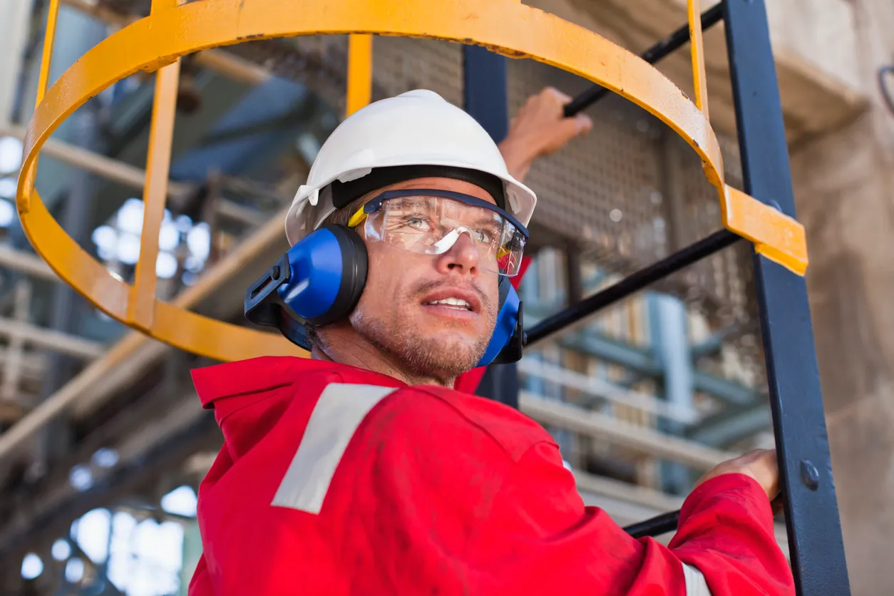 Trabajador climbing escalera en la refinería de petróleo