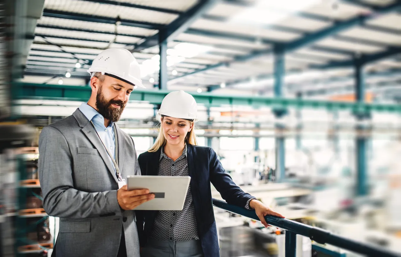 Un retrato del ingeniero industrial del hombre y la mujer con la tablet en una fábrica, trabajando. 