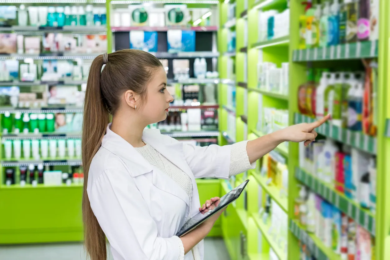 Mujer joven buscando un producto en el estante en una farmacia