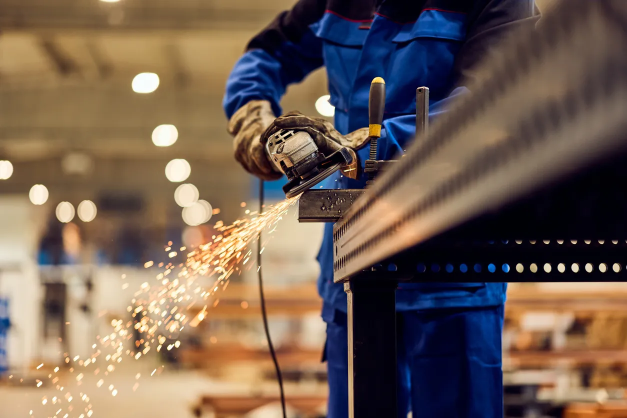 Trabajador que usa una amoladora angular en chispas productoras de metal en un entorno industrial -