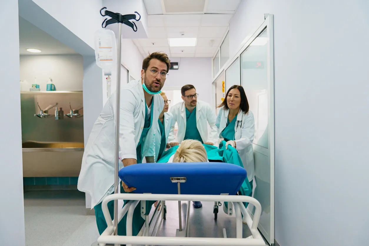 Mujer caucásica mayor en camilla de hospital con equipo médico en la sala de emergencias