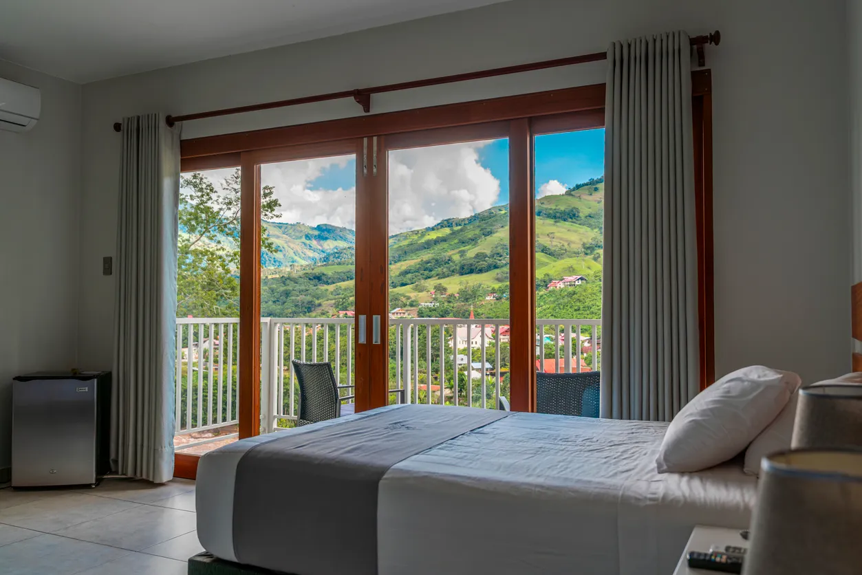 Dormitorio moderno de hotel con vistas a la montaña desde balcón,