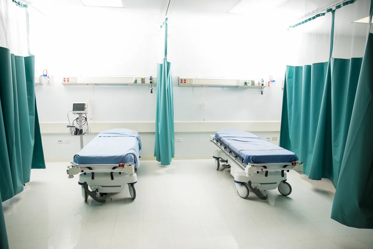 Sala de emergencias vacía en un hospital, con un par de camas con sábanas desechables. 