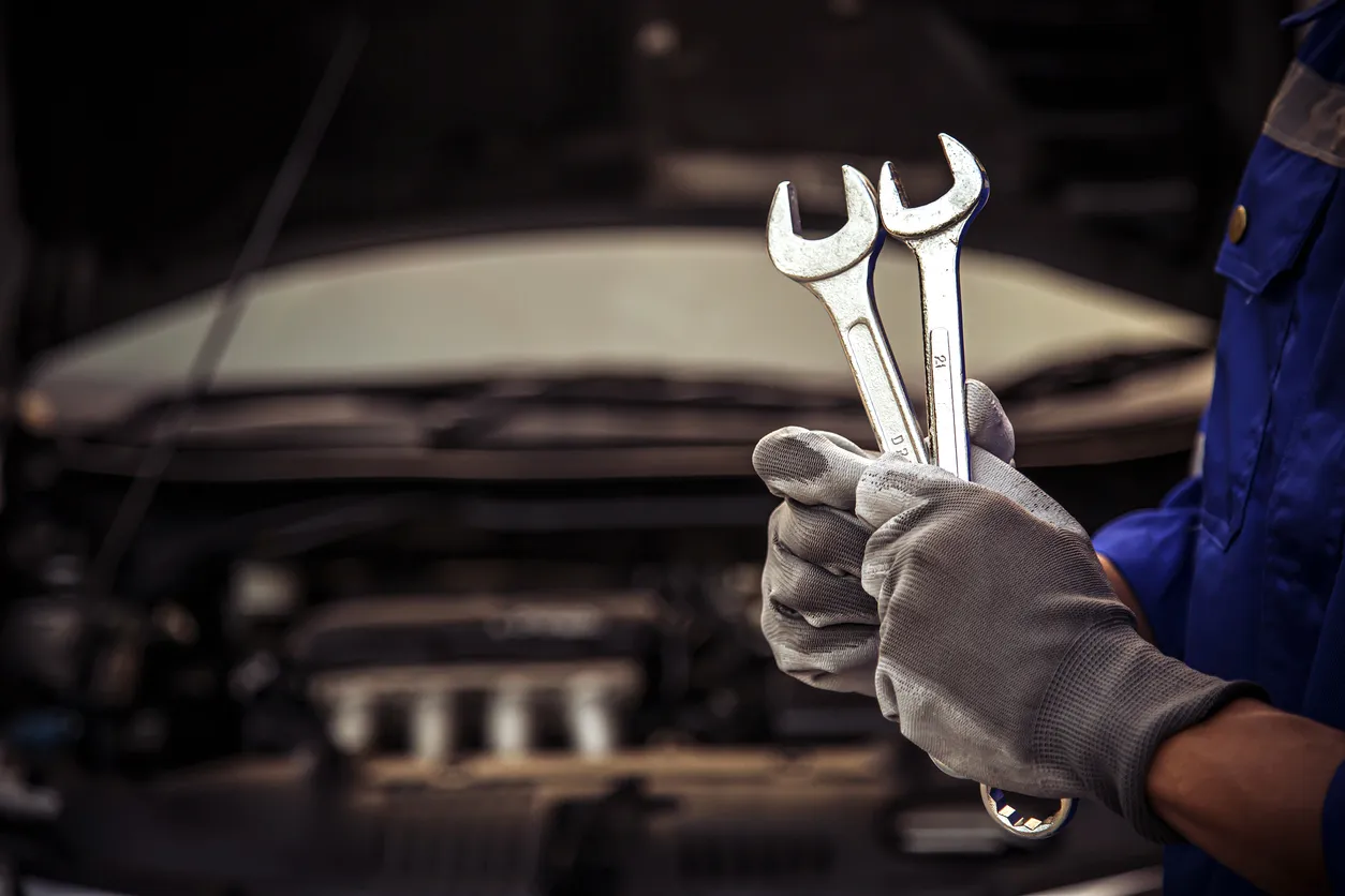 Mantenimiento y servicio de cuidado del automóvil, mecánico de automóviles técnico de mano de primer plano que usa la llave 