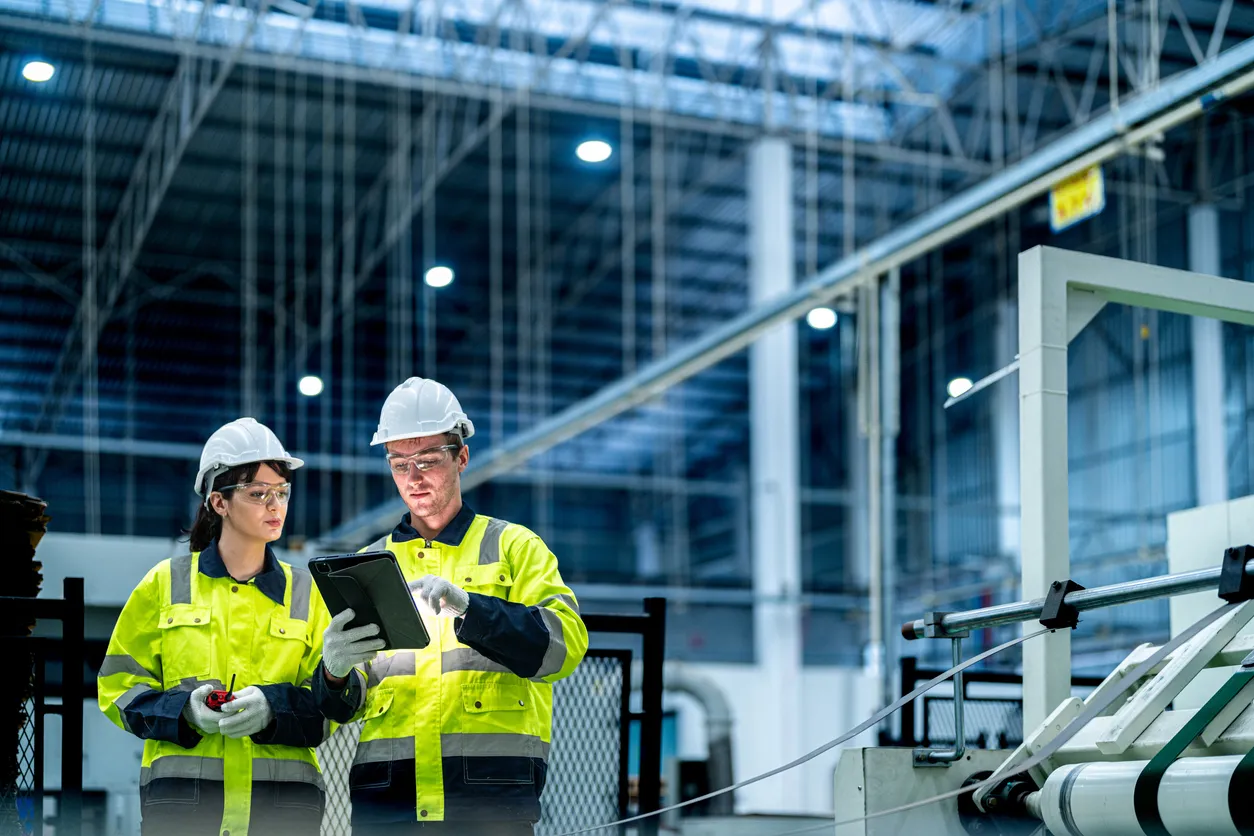 Ingenieros y ingenieras con ropa de trabajo impecable preparan y controlan el sistema de producción de grandes máquinas 