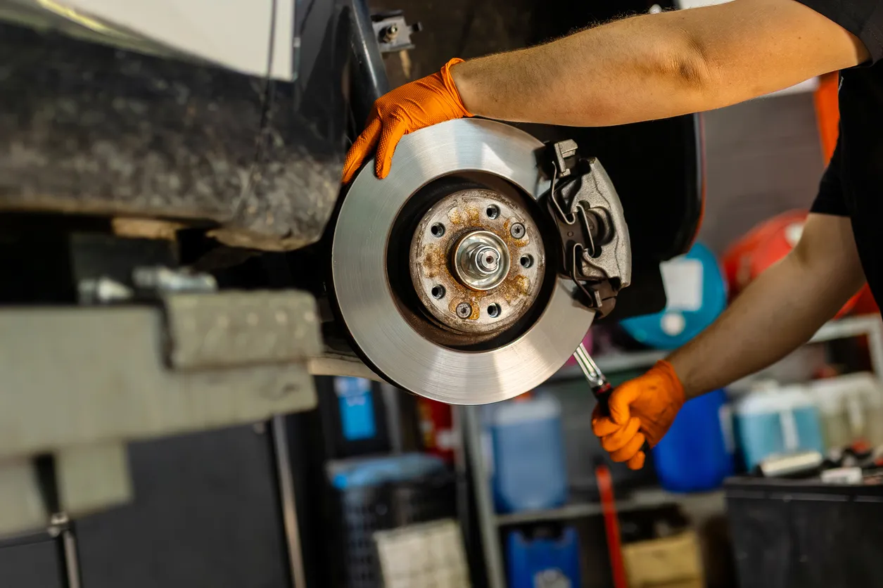 Mecánico trabajando en un disco de freno de coche en taller de automóviles 