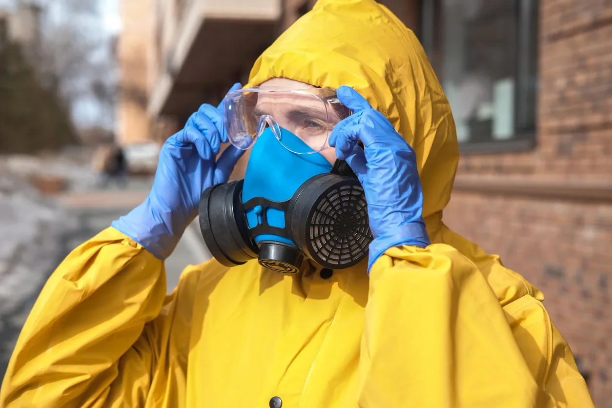 Virólogo en traje amarillo protector y respirador en las calles de la ciudad. El doctor lleva gafas, guantes y una máscara.