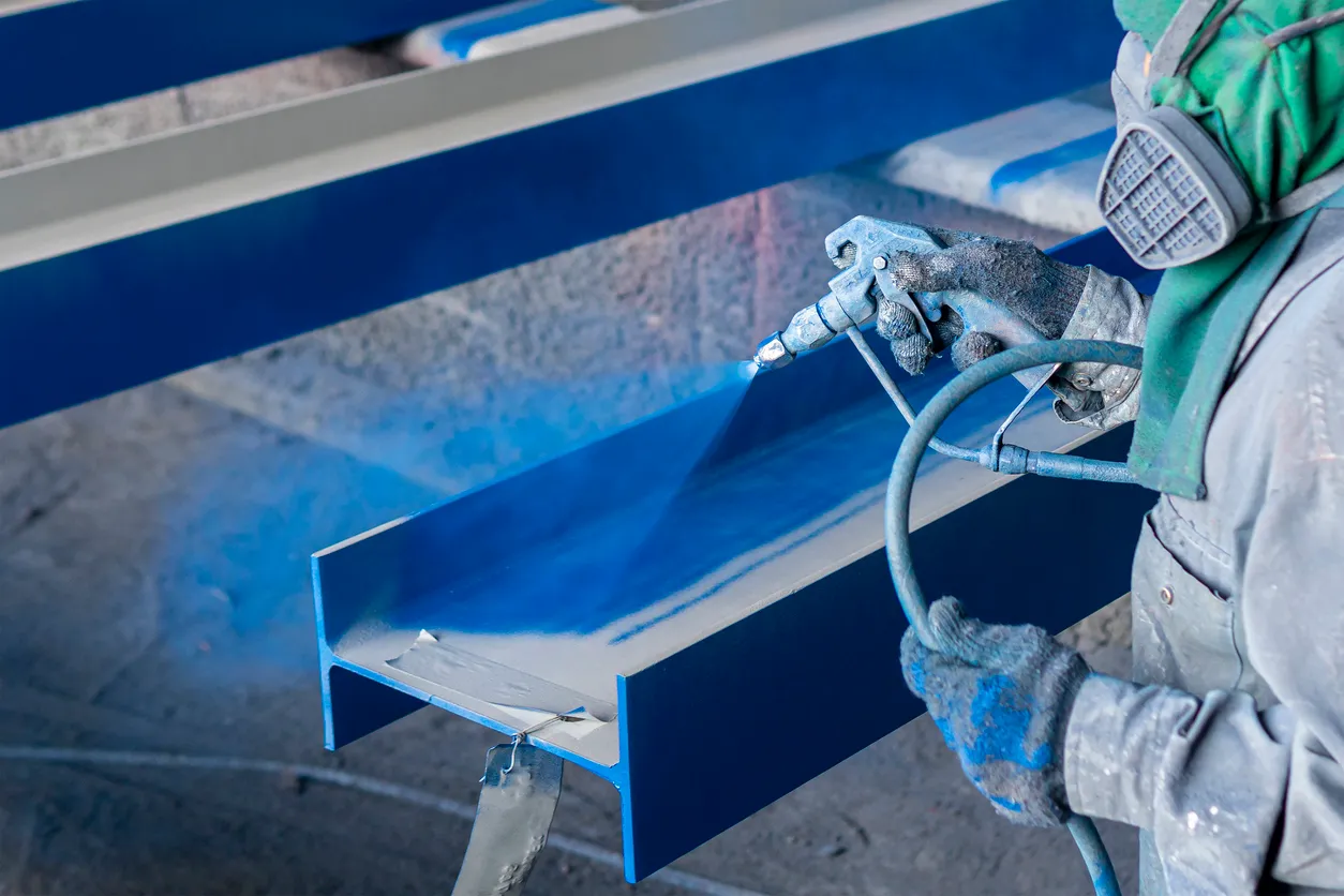 Pintura de la capa superior de color sobre la estructura de acero con pistola de pulverización en la fábrica industrial