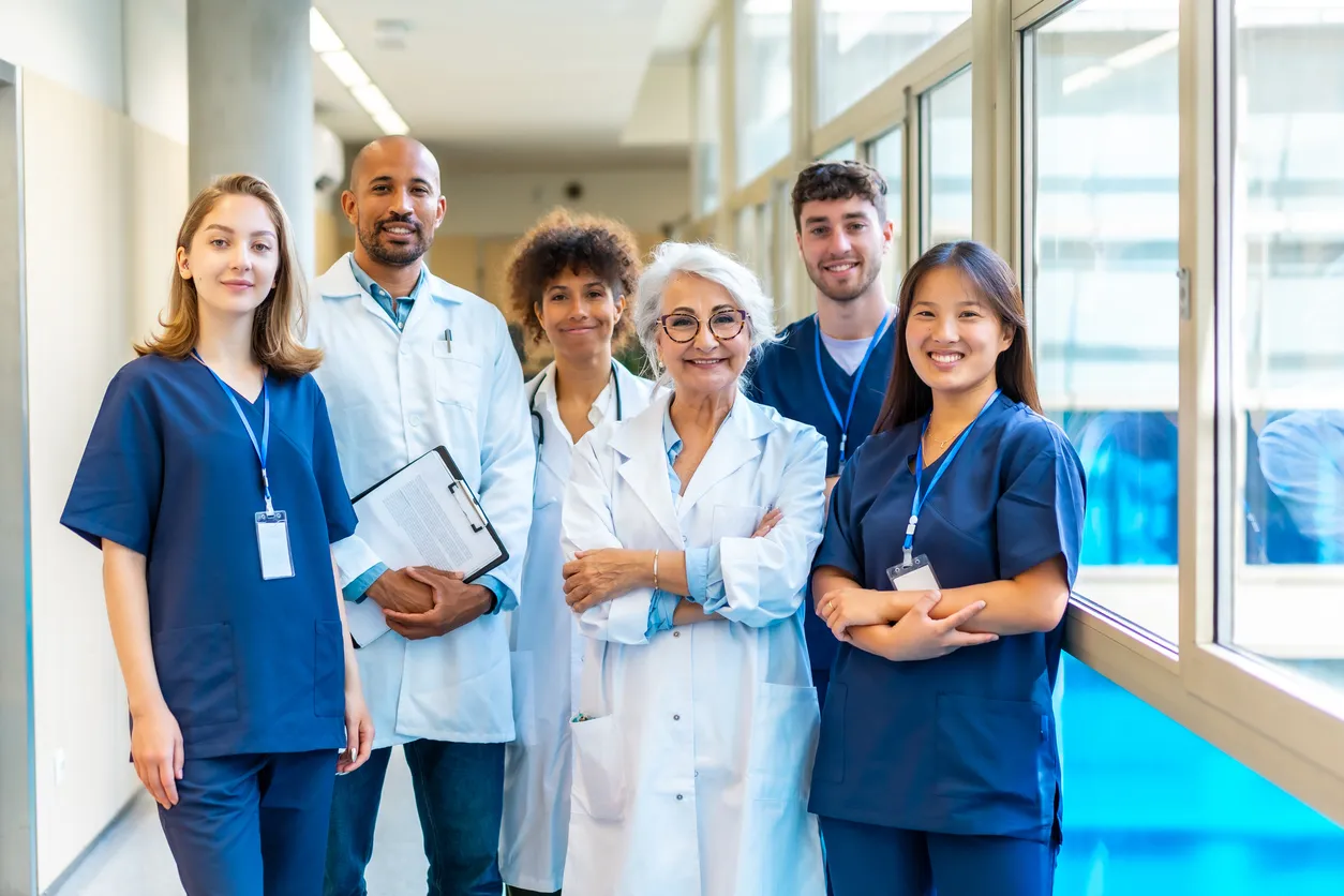 Equipo médico sonriendo a la cámara en el pasillo del hospital 