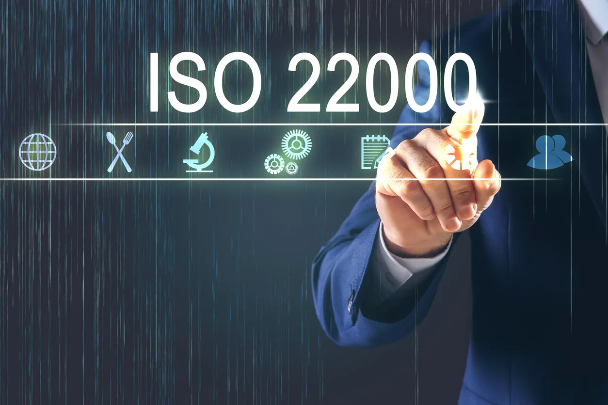 Hombre apuntando a la pantalla virtual con texto ISO 22000 y diferentes iconos, primer plano