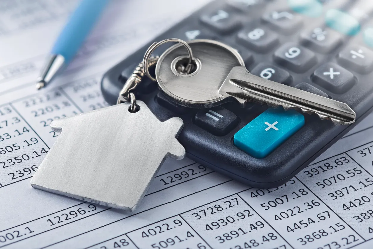 Inmobiliaria, llavero con símbolo de casa. Clave con finanzas en blanco