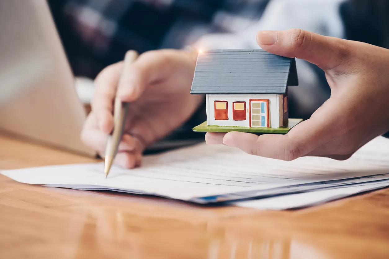 Cierre el agente inmobiliario con la mano modelo de la casa que pone el contrato de firma