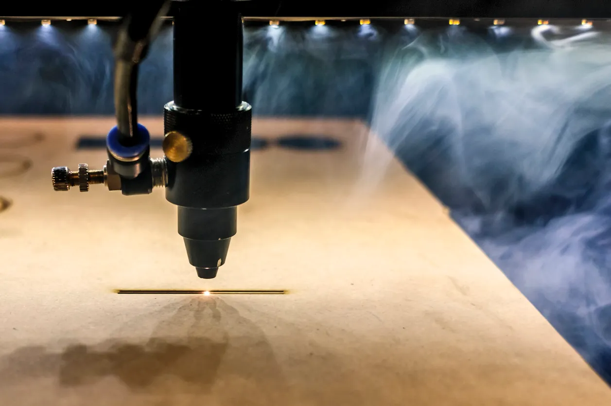 cañón láser cortando diversos materiales, se aprecian el movimiento, la luz intensa y el humo del material que se vaporiza 