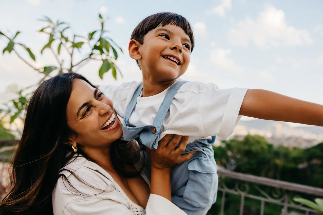 Madre latina e hijo disfrutando de un momento de juego juntos al aire libre en un día soleado
