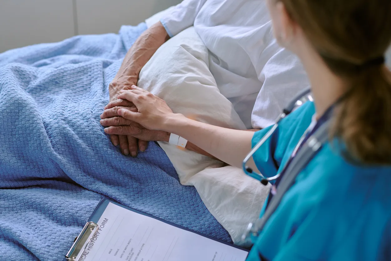 Enfermera de mediana edad que consuela a un hombre caucásico mayor en la cama del hospital 