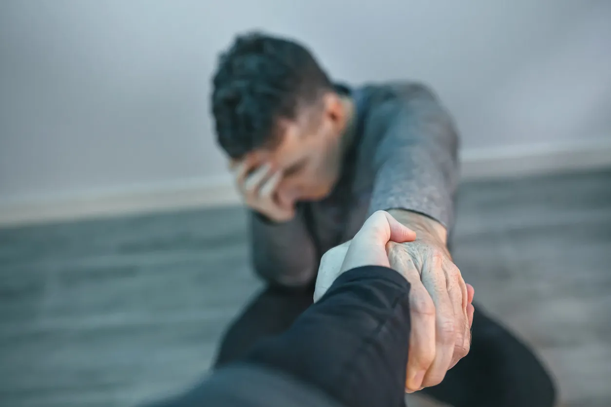 Hombre irreconocible con problemas para recibir ayuda de una mujer que la toma de la mano
