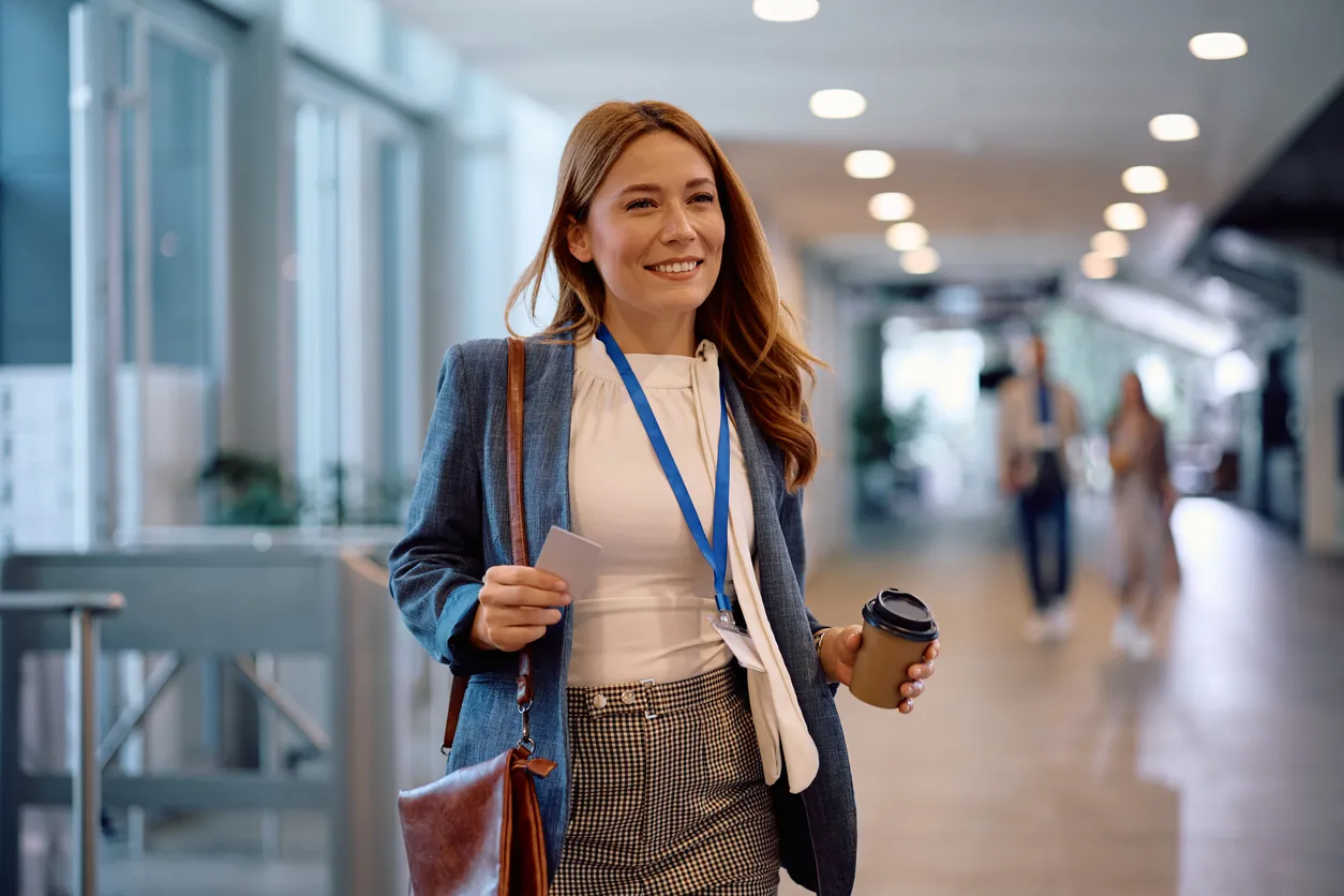 Feliz empresaria que lleva café para llevar mientras viene a trabajar a la oficina