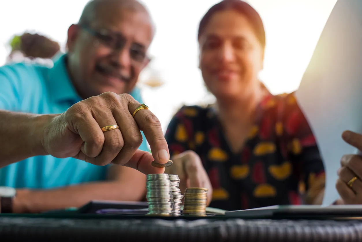Pareja de adultos apilando monedas como representación del ahorro