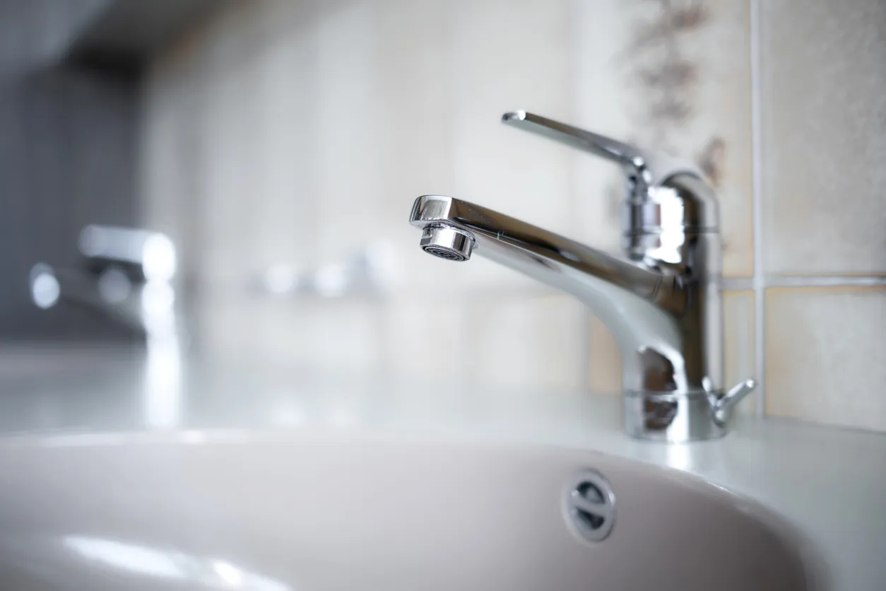 Grifo de agua cromado brillante en el interior del baño del apartamento