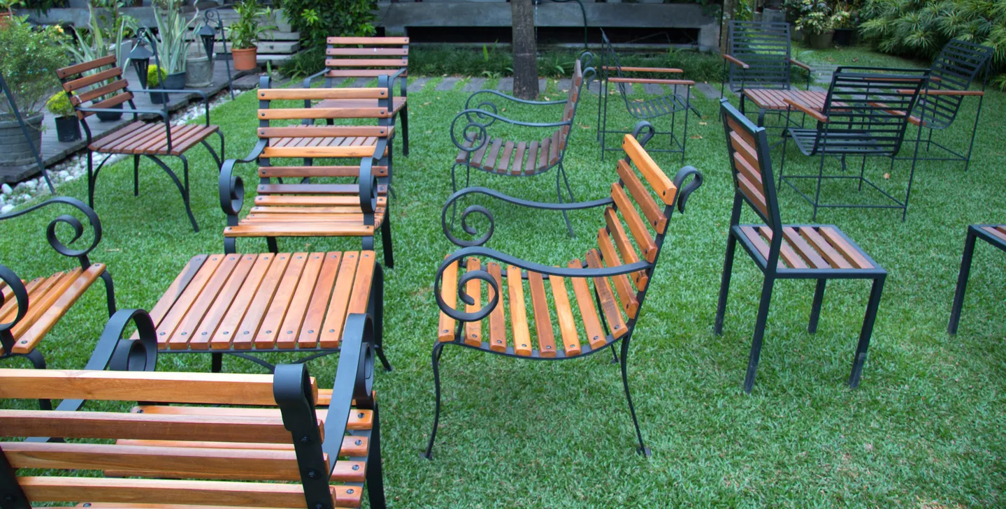 Jardín con hermosas mesas y sillas de fierro y madera