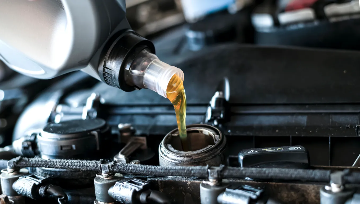 Primer plano de verter aceite de motor sintético en motor diesel. 