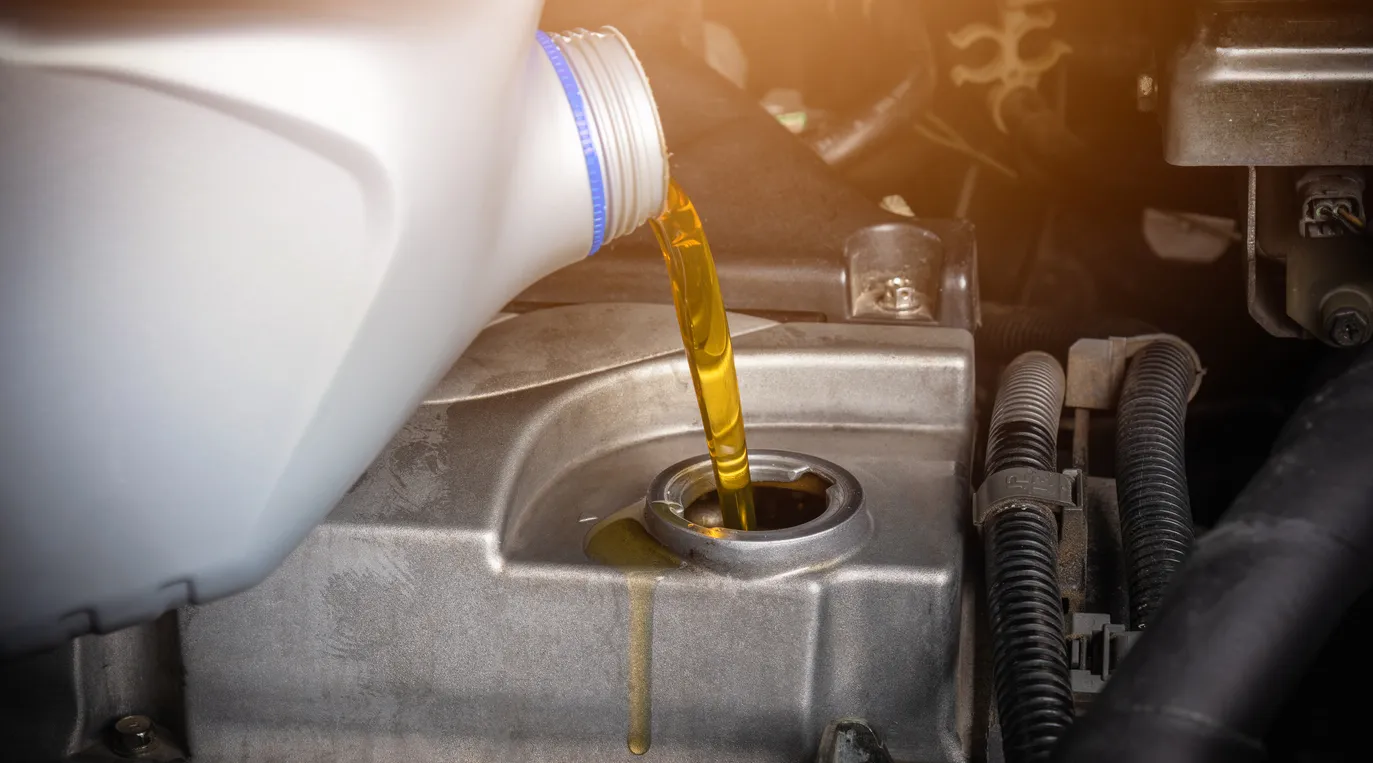 Mecánico manual en servicio para reparar un coche, vertiendo aceite lubricante de cambio