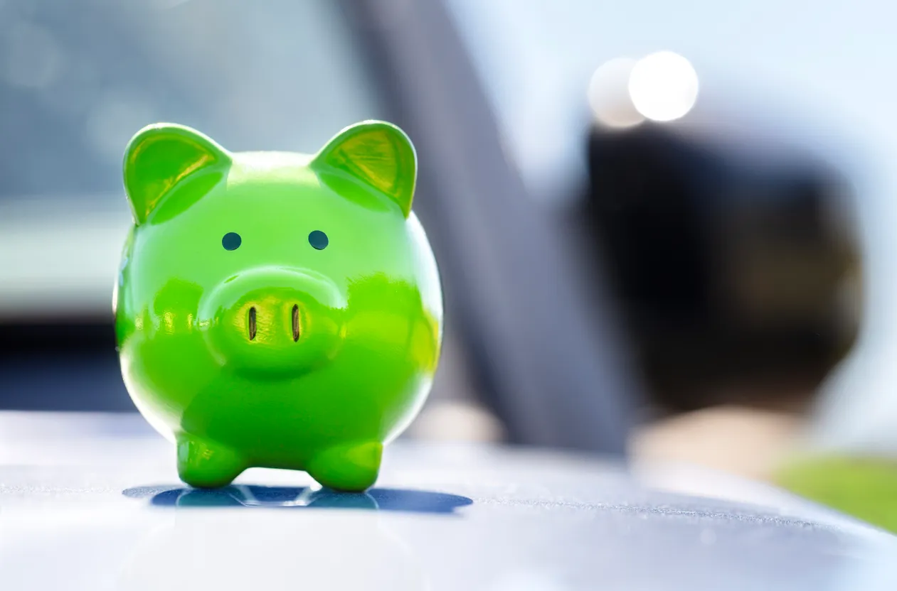 Caja de dinero de alcancía verde en la parte superior del capó del automóvil