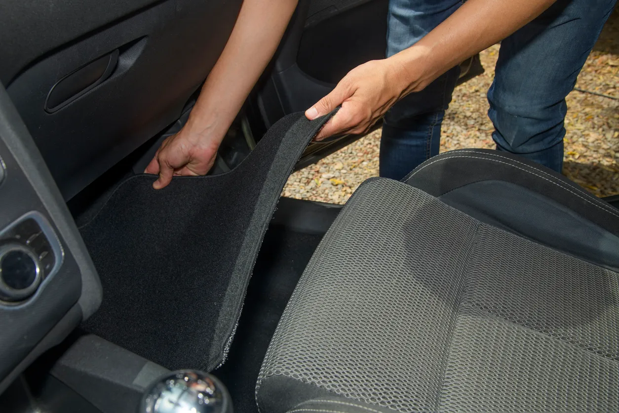Un hombre coloca la nueva alfombrilla del coche 