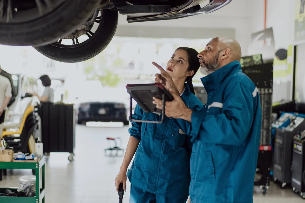 Mecánicos revisando la parte inferior de un auto