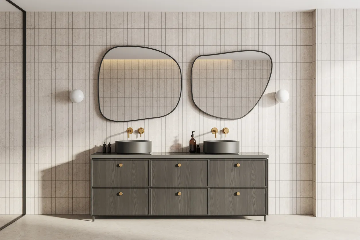 Dos enormes espejos de forma irregular en baño moderno encima de mueble conn lavabo de encimera