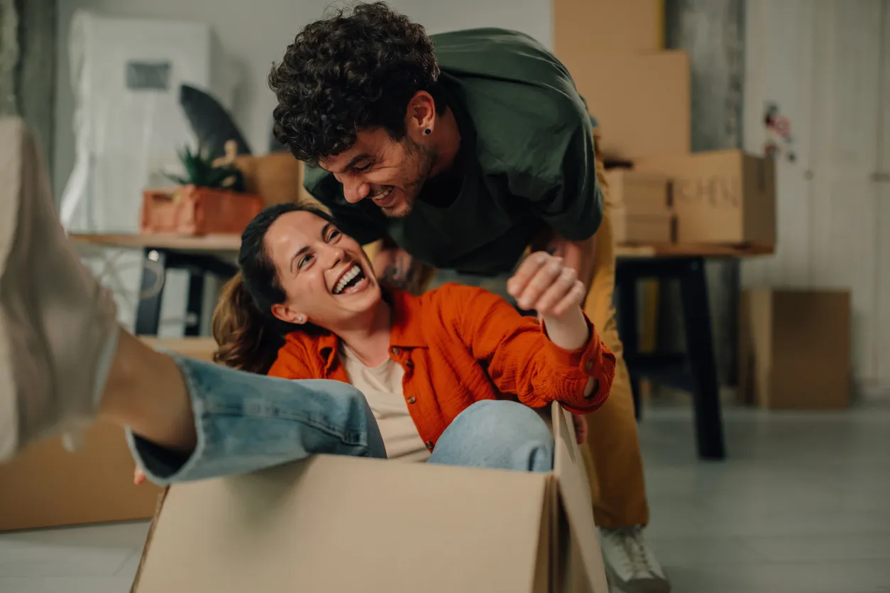 Pareja feliz divirtiéndose mientras se muda a un nuevo hogar