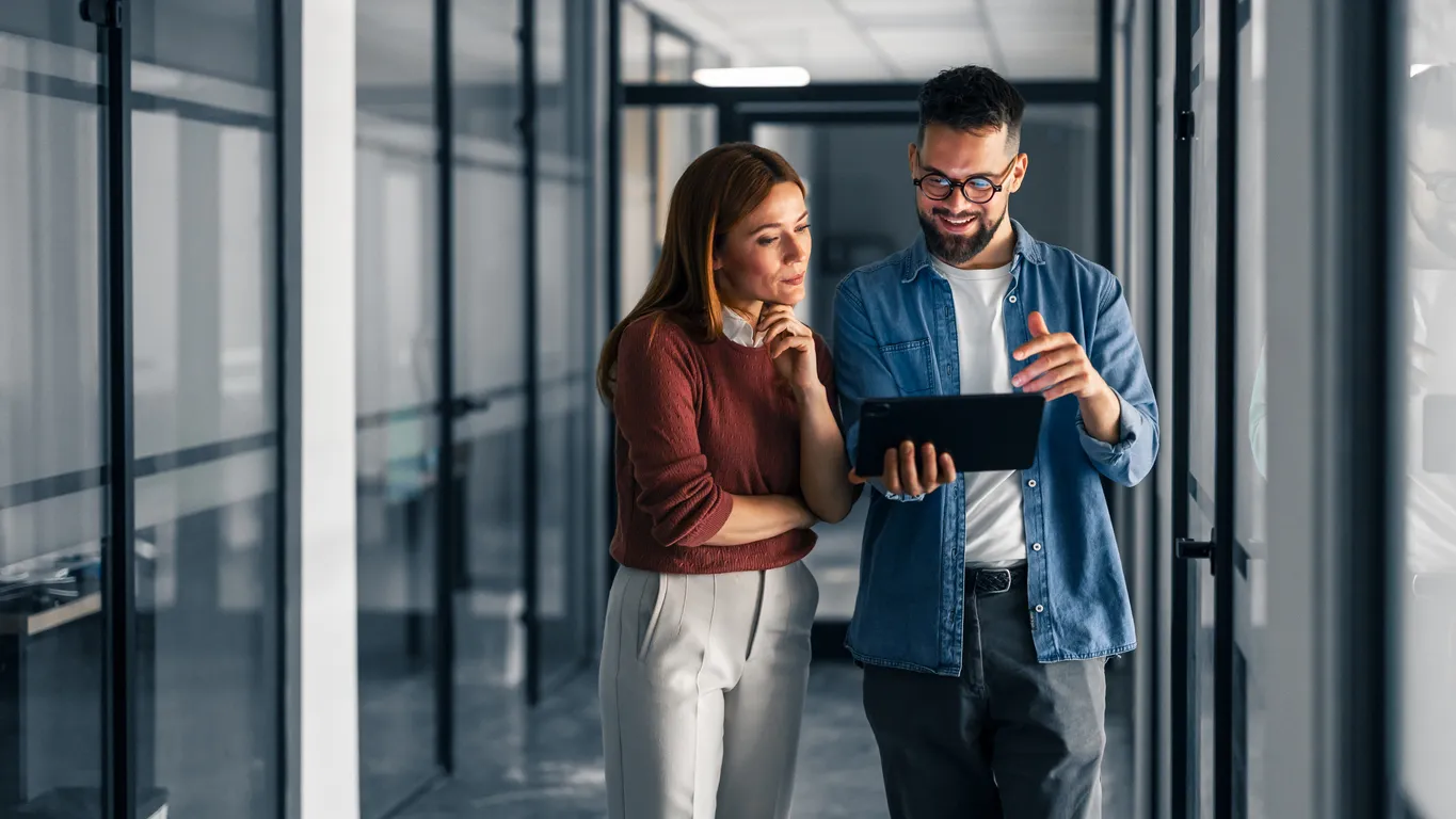Dos profesionales hablan sobre el trabajo usando una tableta digital en una oficina