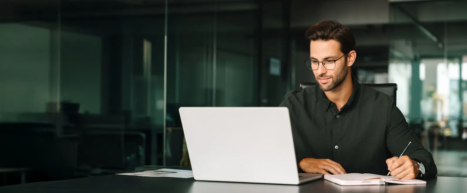 Joven adulto europeo mirando la pantalla del portátil y del ordenador. 