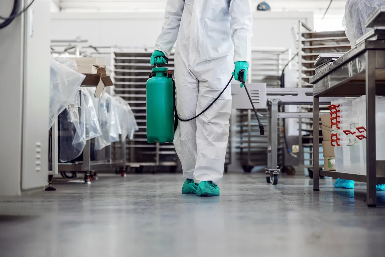 Hombre en traje protector y máscara almacén desinfectante lleno de productos alimenticios