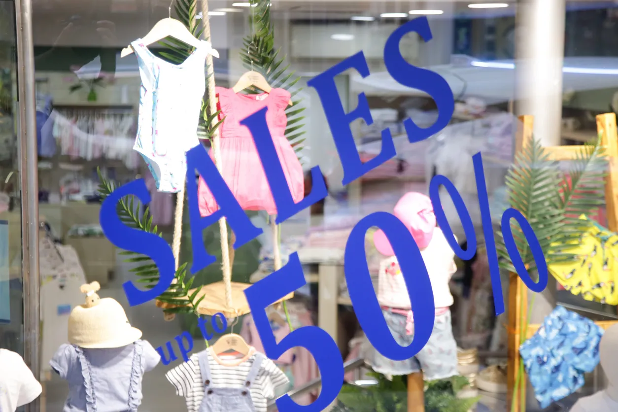 Anuncio de oferta en exhibidor de ropa de una tienda de bebés