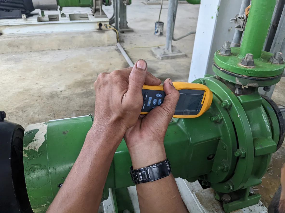 El trabajador mide el motor de vibración y la bomba en el proyecto de la planta de energía. 