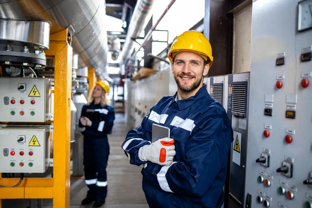 ingeniero eléctrico industrial de pie junto a la fuente de alimentación dentro de la refinería de petróleo
