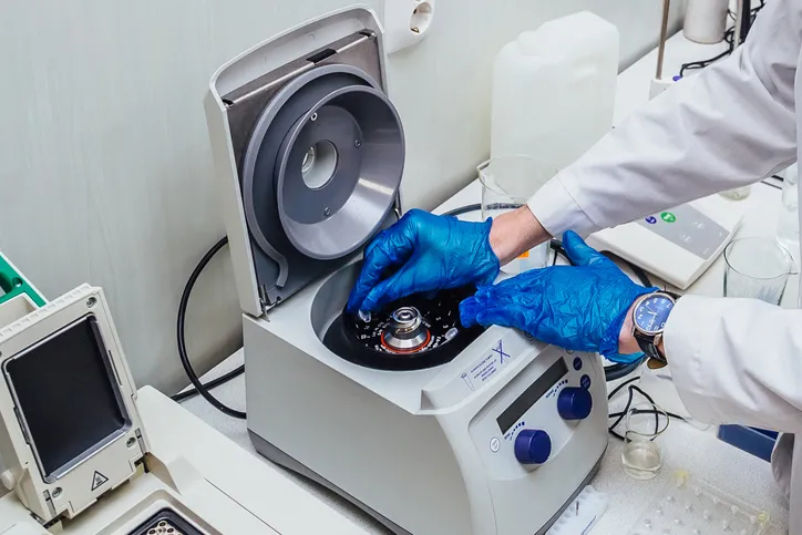 Científico colocando tubos de ensayo con muestras de ADN en una centrífuga.