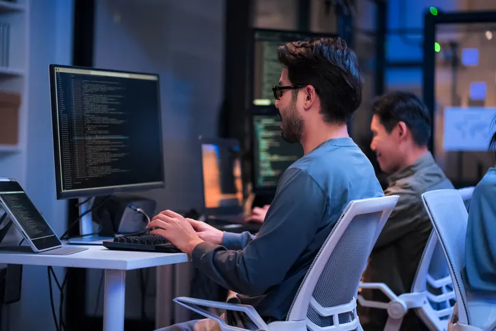 Dos ingenieros frente a sus monotores codificando un programa