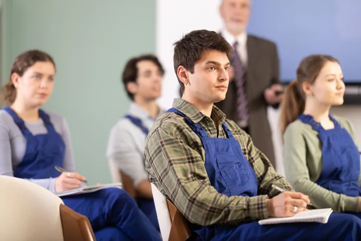 varios jovenes con overol tomando clase