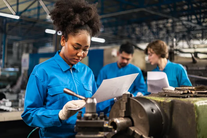 Joven trabajadora estudiando y practicando en su área de trabajo en fábrica