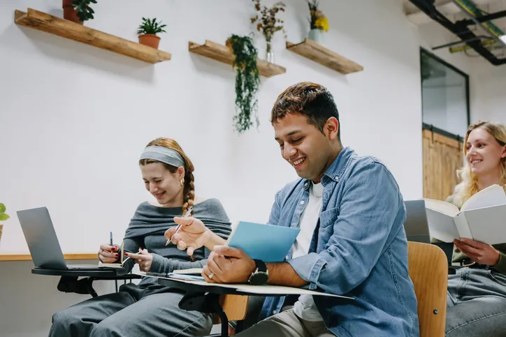 hombre y mujeres estudaindo en sala de capacitación