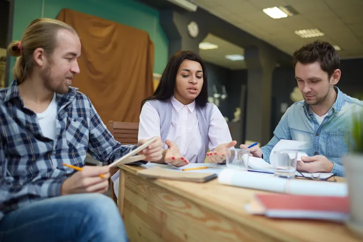 trabajadores estudiando alrrededor de una mesa de trabajo en un taller de la fábrica